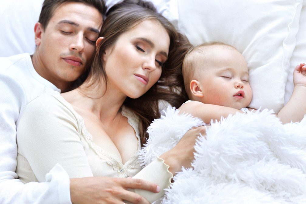 Ύπνος νεογέννητου μωρού με γονείς. Κοιμούνται και οι τρεις αγκαλιασμένοι σε κρεβάτι.